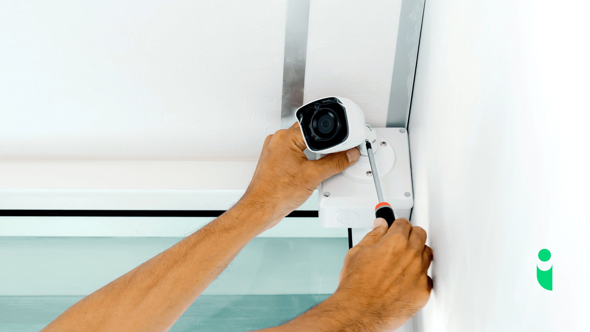 Person's hands screwing in security camera inside 